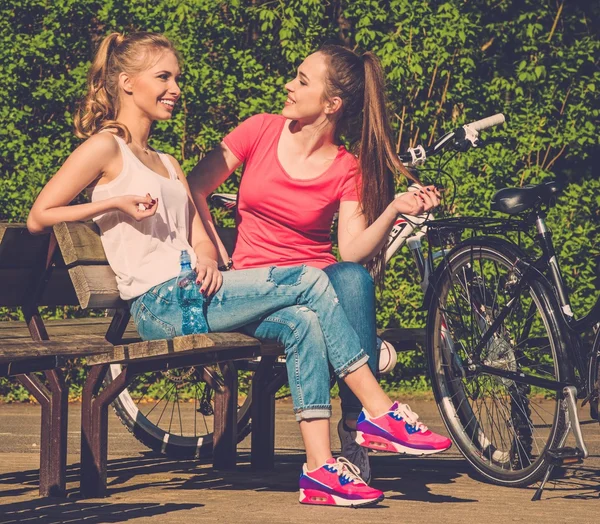 Två glada tonårsflickor med cyklar i en park — Stockfoto