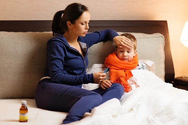 Genç anne ve bir yatakta hasta oğlu — Stok fotoğraf