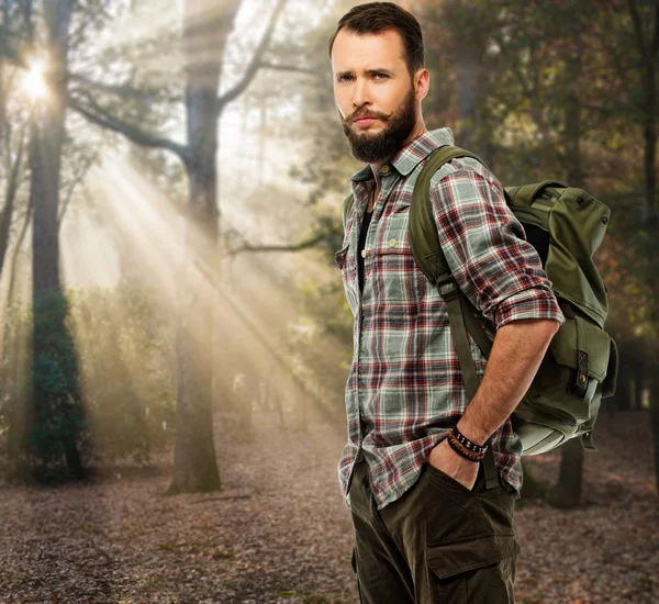 Handsome traveler with backpack in autumnal forest — Stock Photo, Image