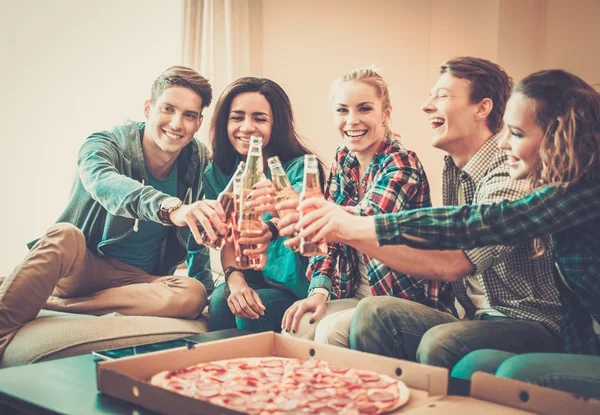 Gruppo di giovani amici multietnici con pizza e bottiglie di bevande che festeggiano in casa — Foto Stock