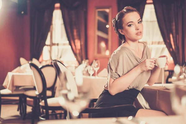 Belle jeune femme avec une tasse de café seule dans un restaurant — Photo