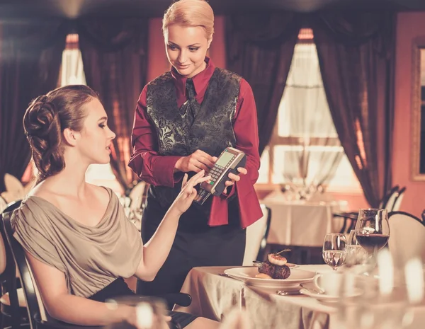 Beautiful young woman paying with card in a restaurant — Stock Photo, Image