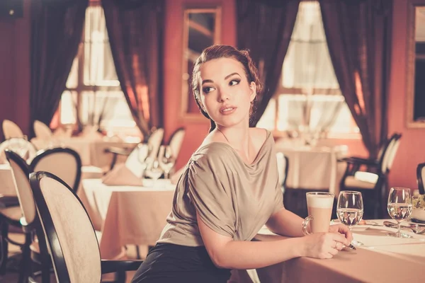 Schöne junge Frau mit einer Tasse Kaffee allein in einem Restaurant — Stockfoto