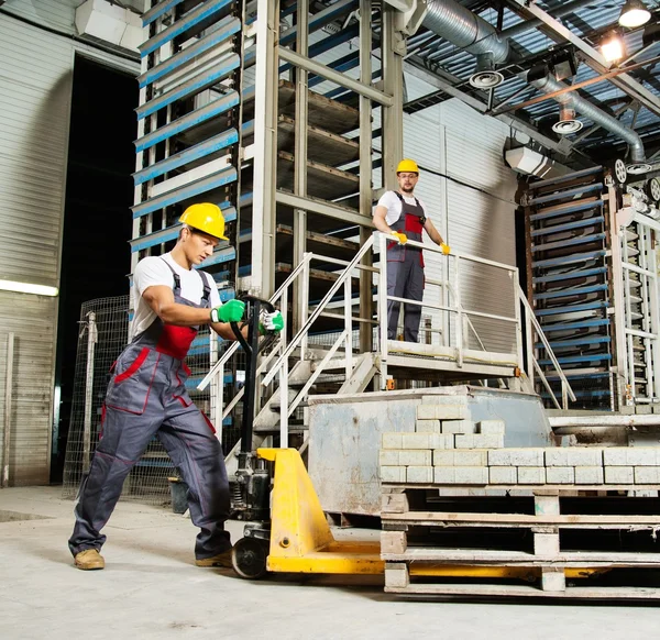 Jonge werknemers straatstenen met pallettruck bewegen op een fabriek — Stockfoto