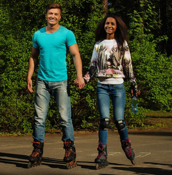 Мультинациональная подростковая пара на роликах в парке — стоковое фото