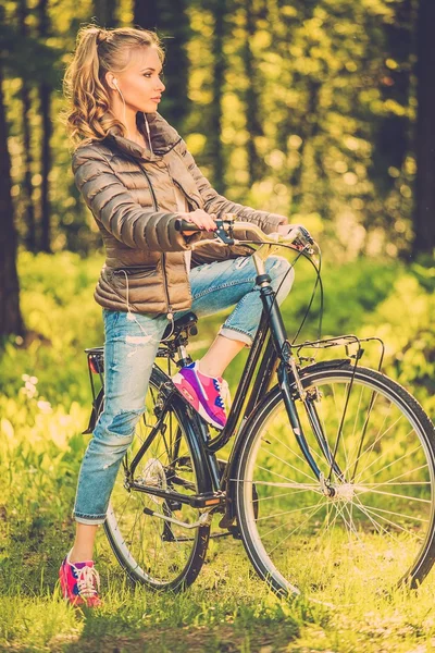 Glada tonåring flicka lyssnar musik på en cykel utomhus — Stockfoto