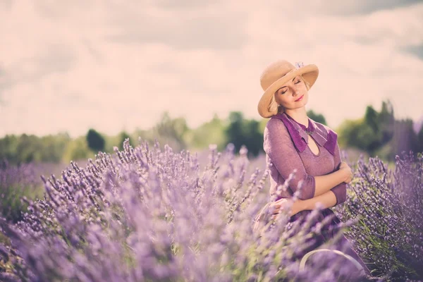 Vrouw in paarse jurk en hoed met mandje in Lavendel veld — Stockfoto