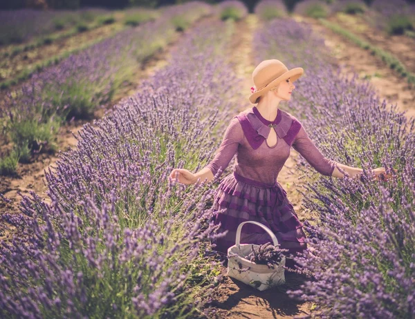 Mulher de vestido roxo e chapéu com cesta no campo de lavanda — Fotografia de Stock