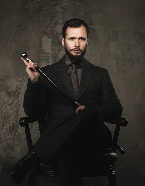 Handsome well-dressed with stick sitting in leather chair — Stock Photo, Image