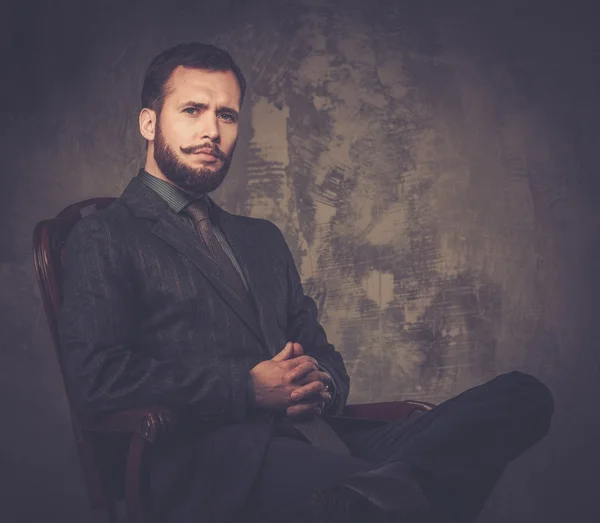 Handsome well-dressed with stick sitting in leather chair — Stock Photo, Image