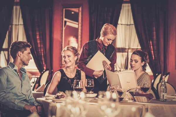 Grupo de jovens amigos com menus escolhendo em um restaurante de luxo — Fotografia de Stock