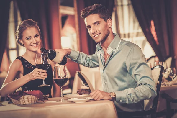 Vackra unga par med glas rött vin i lyx restaurang — Stockfoto