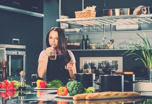Молодая женщина в фартуке на современной кухне нюхает оливковое масло — стоковое фото