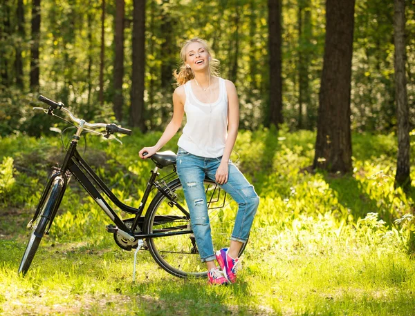 Ler tonårsflicka med cykel i en park på solig dag — Stockfoto