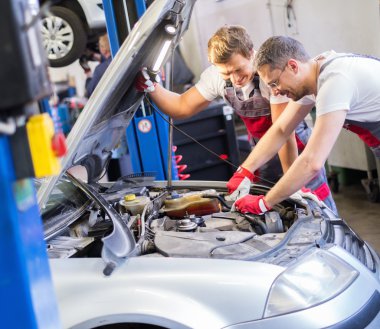 Two mechanics fixing car in a workshop clipart