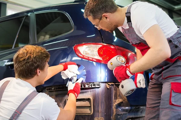 Doi lucrători cu mostre de culoare care aleg nuanța corectă într-un atelier de caroserie auto — Fotografie, imagine de stoc