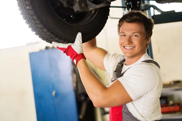 Fröhlicher Servicetechniker überprüft Fahrwerk in einer Autowerkstatt — Stockfoto