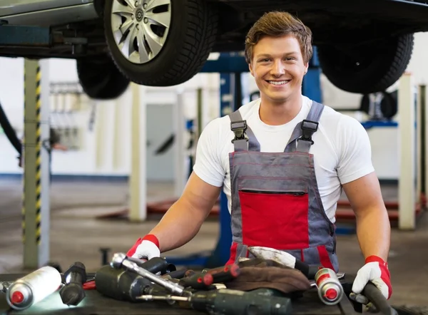 Jonge mechanic met hulpprogramma's in een auto-workshop — Stockfoto