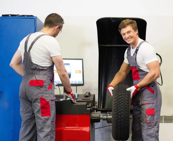 Zwei Mechaniker wuchten Rad in einer Autowerkstatt — Stockfoto