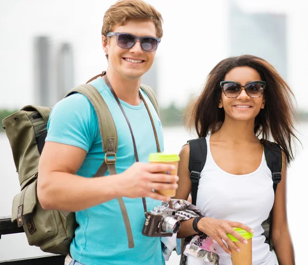 Multi-ethnic friends tourists with map and coffee cups near river in a city — Stock Photo, Image