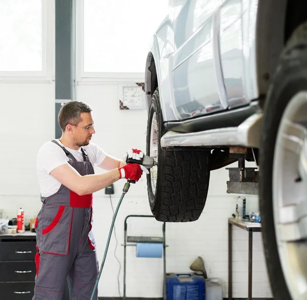 Servicekräfte schrauben Rad in Autowerkstatt ab — Stockfoto