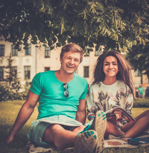 Pareja de estudiantes multiétnicos preparándose para los exámenes finales en un parque de la ciudad —  Fotos de Stock