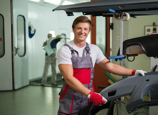 Serviceman with car bodykit ready for painting in a workshop — Stock Photo, Image