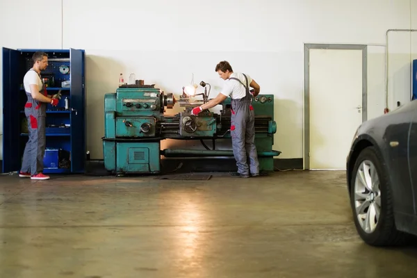 Serviceman working on turning lathe in car workshop — Stock Photo, Image