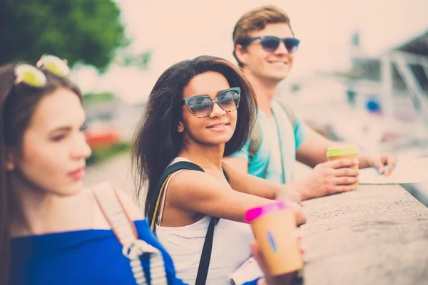 Multiethnische Freunde Touristen mit Karte und Kaffeetassen in Flussnähe in einer Stadt — Stockfoto