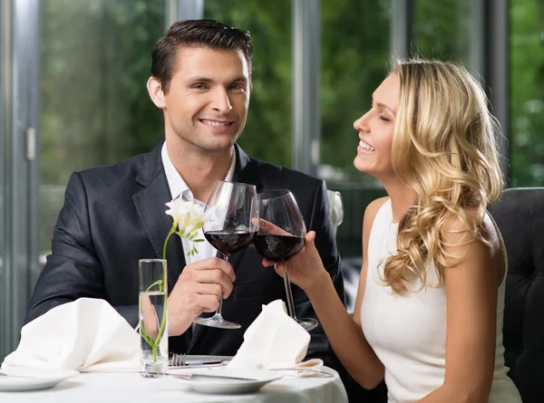 Casal alegre em um restaurante com copos de vinho tinto — Fotografia de Stock