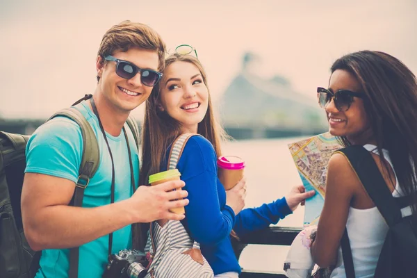 Multiethnische Freunde Touristen mit Karte und Kaffeetassen in Flussnähe in einer Stadt — Stockfoto