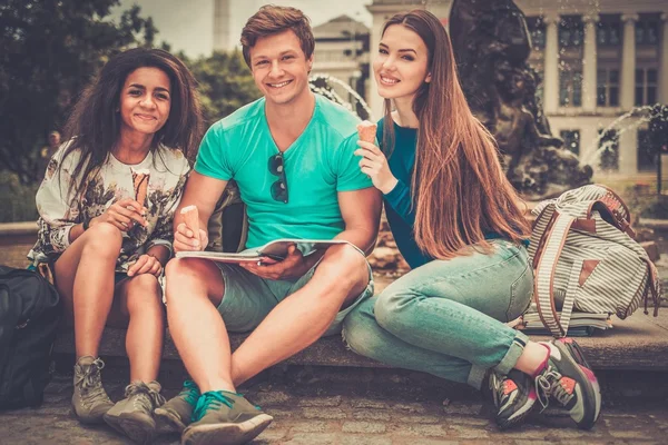 Grupp multi etniska studenter med glass nära fontänen i en park — Stockfoto