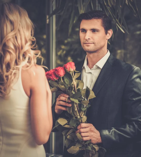 Bonito homem com um monte de rosas vermelhas namoro sua senhora — Fotografia de Stock