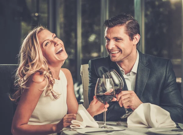 Fröhliches Paar in einem Restaurant mit einem Glas Rotwein — Stockfoto