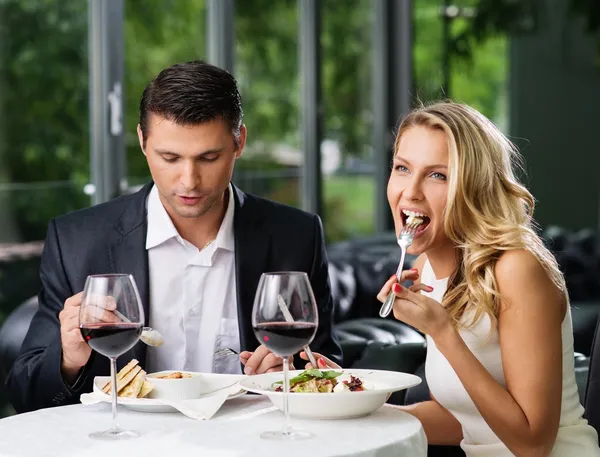 Casal comendo em restaurante com um vinho tinto — Fotografia de Stock