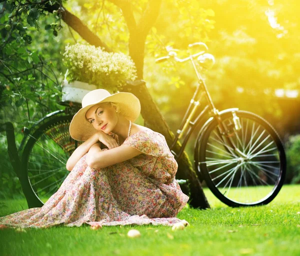 Mulher retro loira bonita com bicicleta atrás dela — Fotografia de Stock