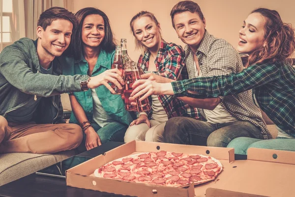 Grupo de jóvenes amigos multiétnicos con pizza y botellas de bebida celebrando en el interior del hogar —  Fotos de Stock