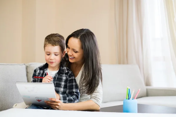 Felice giovane madre con suo figlio disegno in casa interiore — Foto Stock