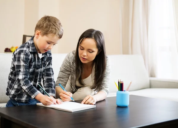 Glückliche junge Mutter mit ihrem Sohn beim Zeichnen zu Hause — Stockfoto