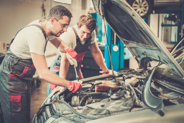 Two mechanics fixing car in a workshop — Stock Photo, Image