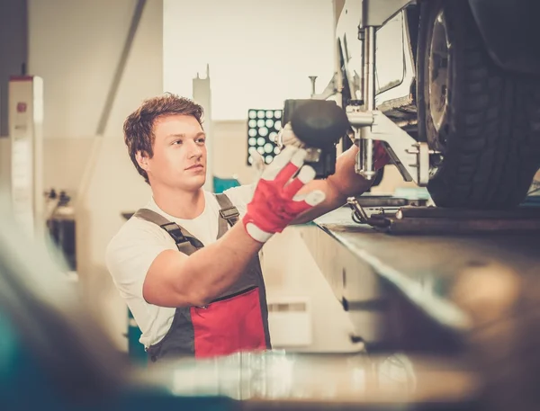 Serviceman checking wheel alignment  in a car workshop — Stock Photo, Image