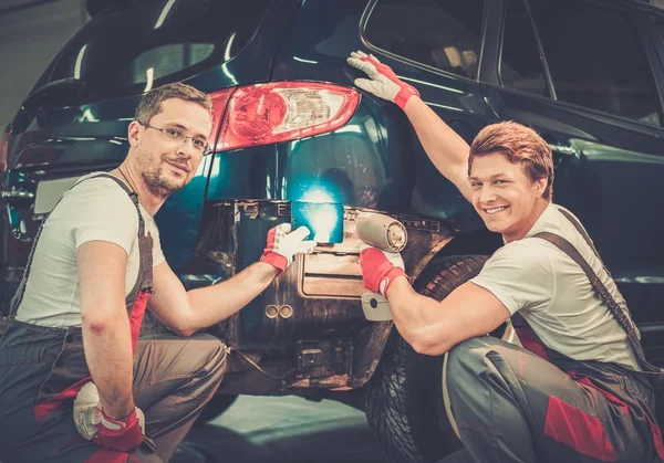 Two workers with colour samples choosing correct tone in a car body workshop — Stock Photo, Image