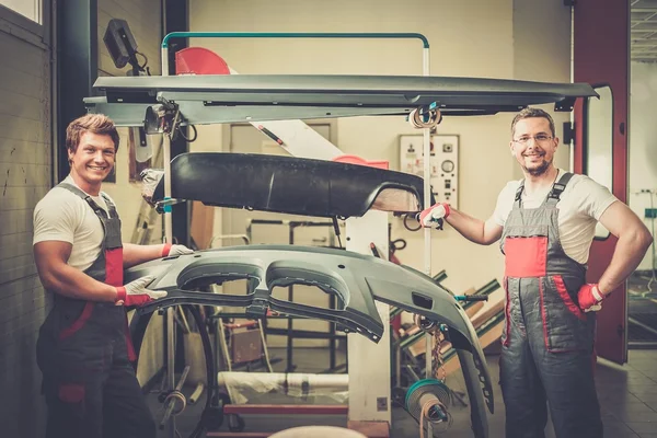 Deux travailleurs avec carrosserie prête à peindre dans un atelier — Photo