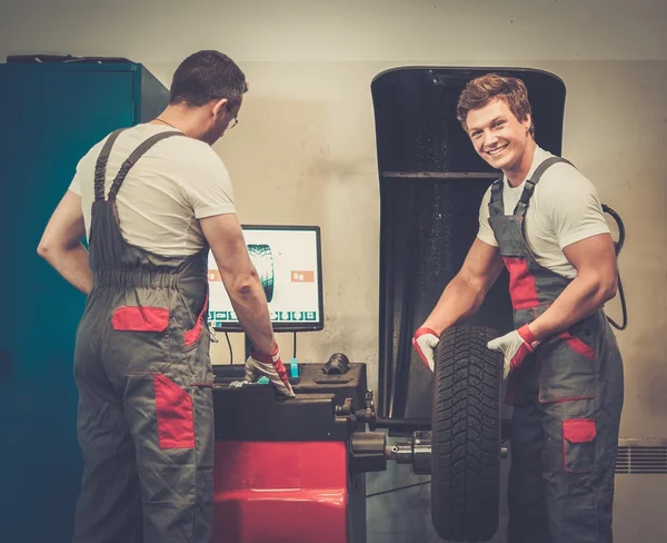 Twee mechanica balancing wiel in een auto-workshop — Stockfoto