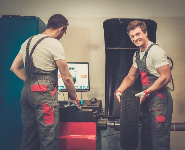 Two mechanics balancing wheel in a car workshop — Stock Photo, Image