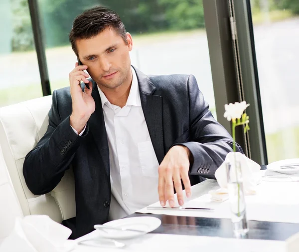 Bonito empresário falando por telefone celular no restaurante — Fotografia de Stock