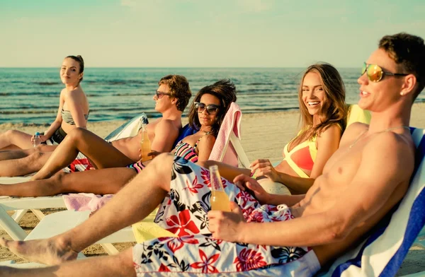 Grupy etniczne przyjaciół multi opalając się na leżaki na plaży — Zdjęcie stockowe