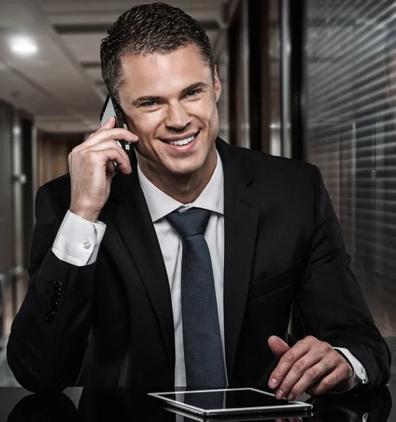 Hombre guapo en traje negro con teléfono móvil y tableta PC en la oficina moderna —  Fotos de Stock