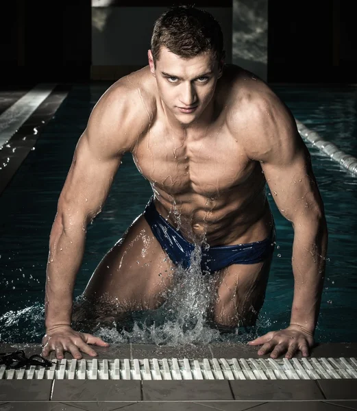 Young muscular swimmer in a swimming pool — Stock Photo, Image