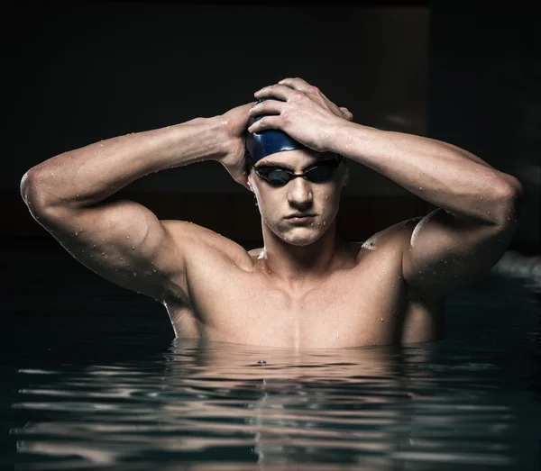 Muscoloso giovane in berretto blu in piscina — Foto Stock